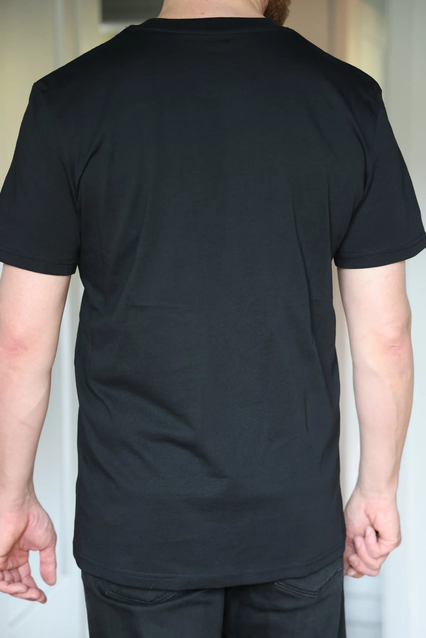 Person wearing a plain black t-shirt against a neutral background