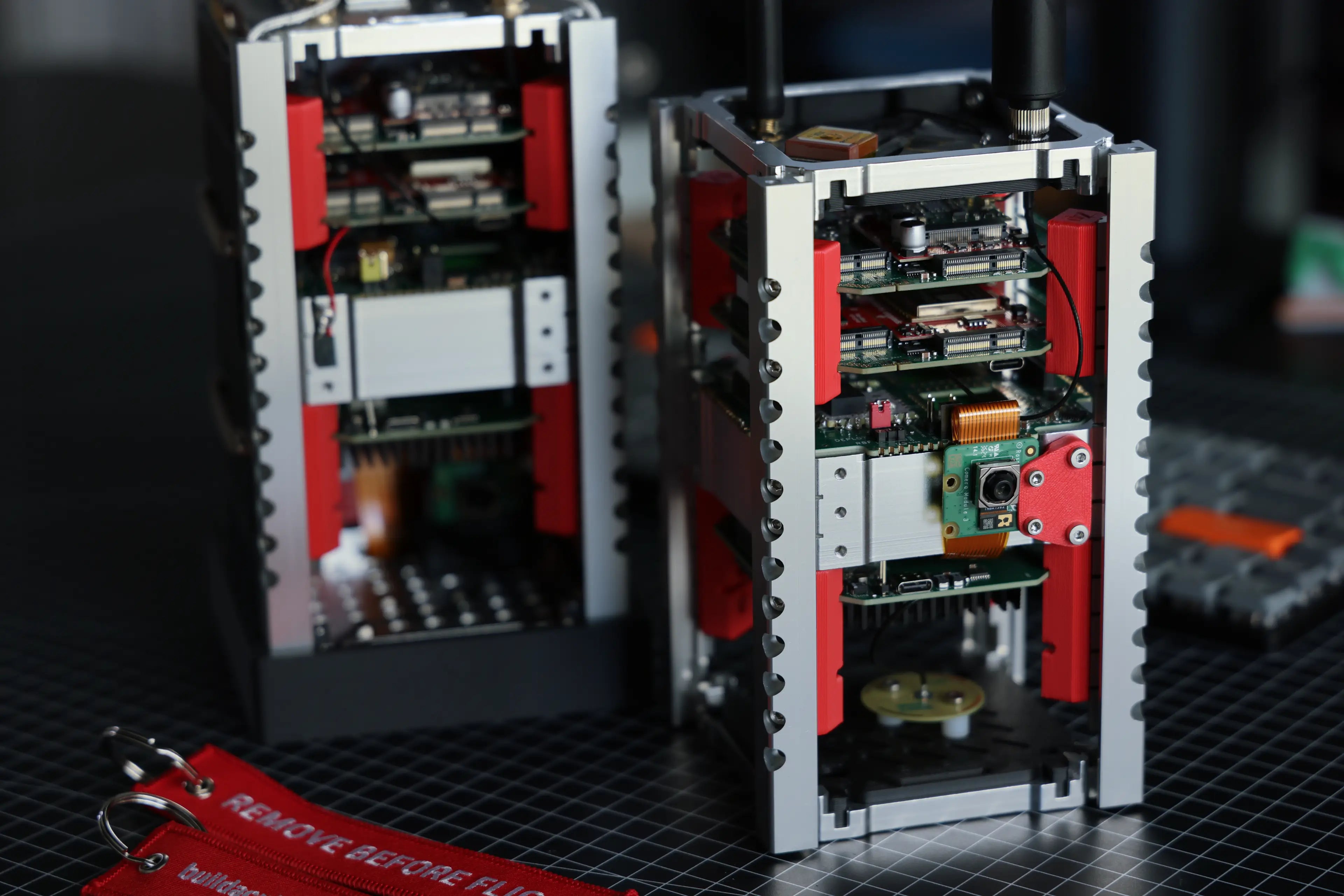 Close-up of two DIY CubeSats with visible internal components on a dark surface.