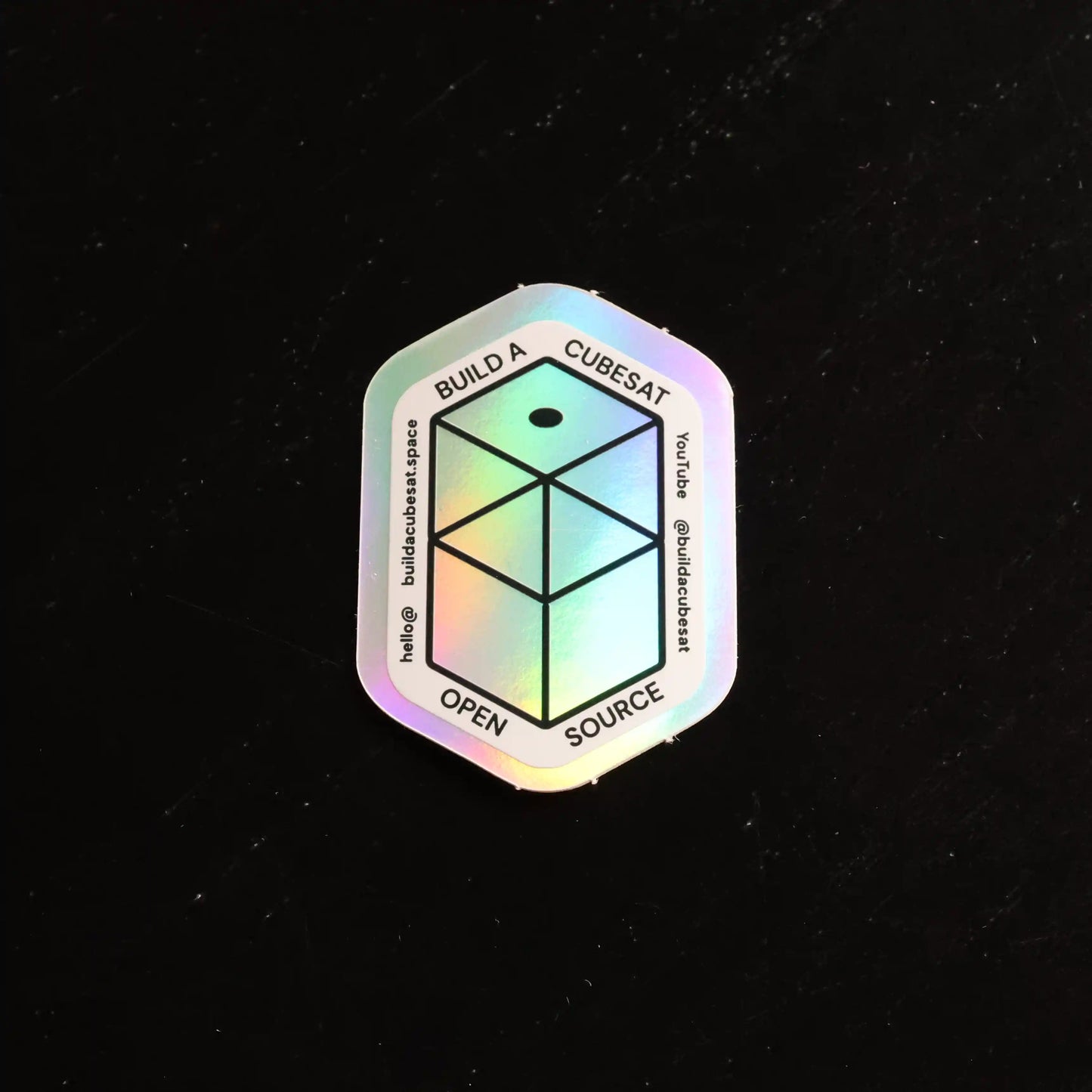 Holographic sticker with geometric design and text on a black background