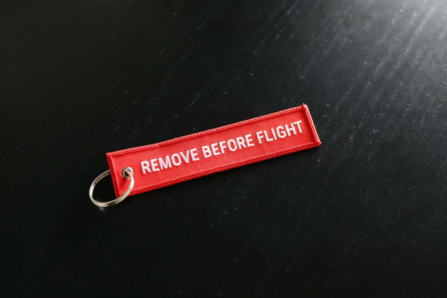 Red 'REMOVE BEFORE FLIGHT' tag on a black background