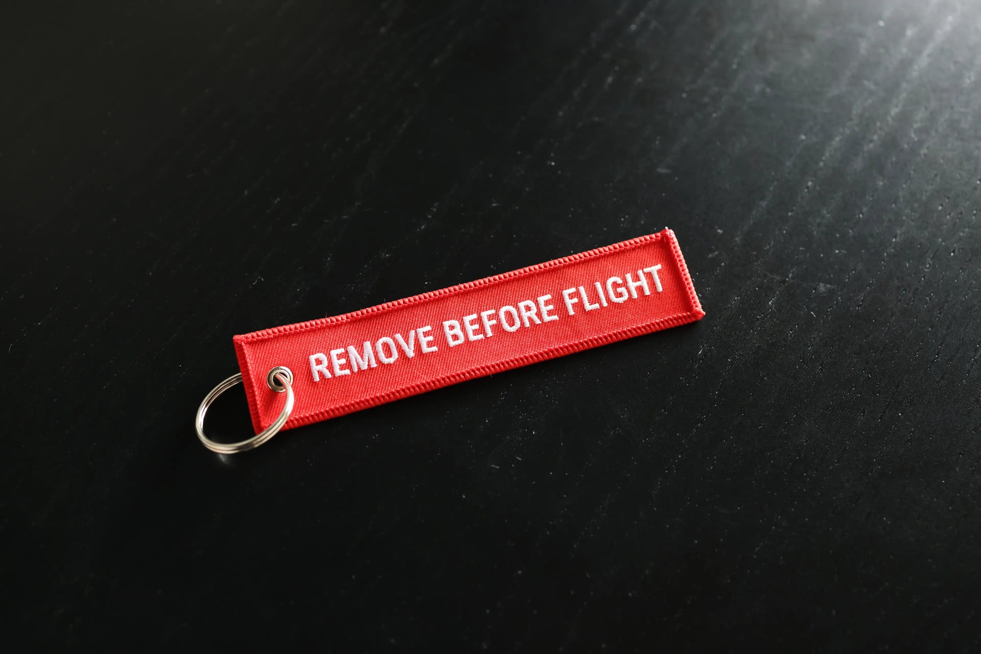 Red 'REMOVE BEFORE FLIGHT' tag on a black background